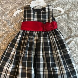 A stylish girl's dress with blak and white plaid pattern , with bold red sash